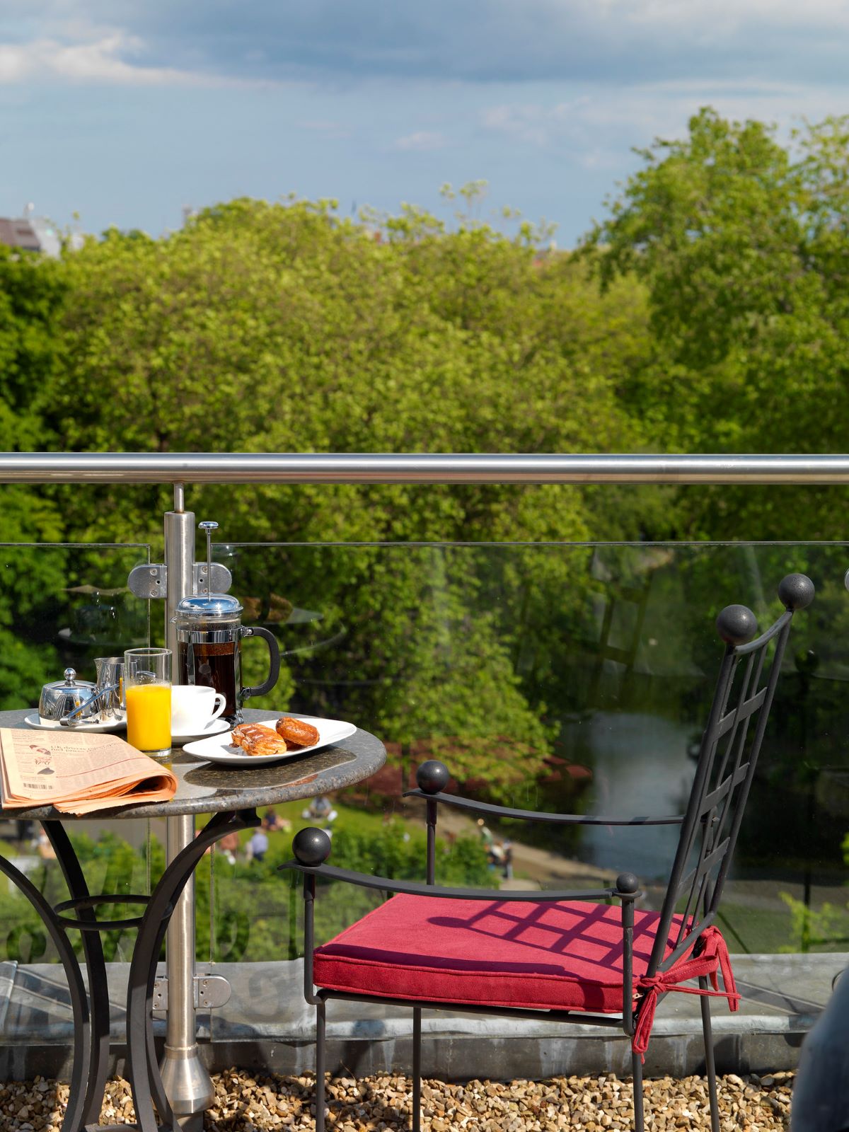 The balcony view at the Fitzwilliam Hotel in Dublin featuring a table and chair and some breakfast and beautiful water and trees in the distance.